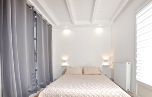 A bedroom with a bed, curtains, two wall-mounted lights, and a radiator. - 1 bedroom gorgeous home in Saint Cyprien Plage (Saint Cyprien Plage)
