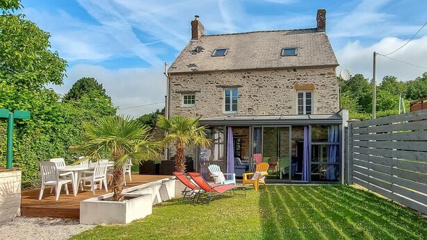 Una casa de piedra con un patio, mobiliario exterior y una puerta de cristal.