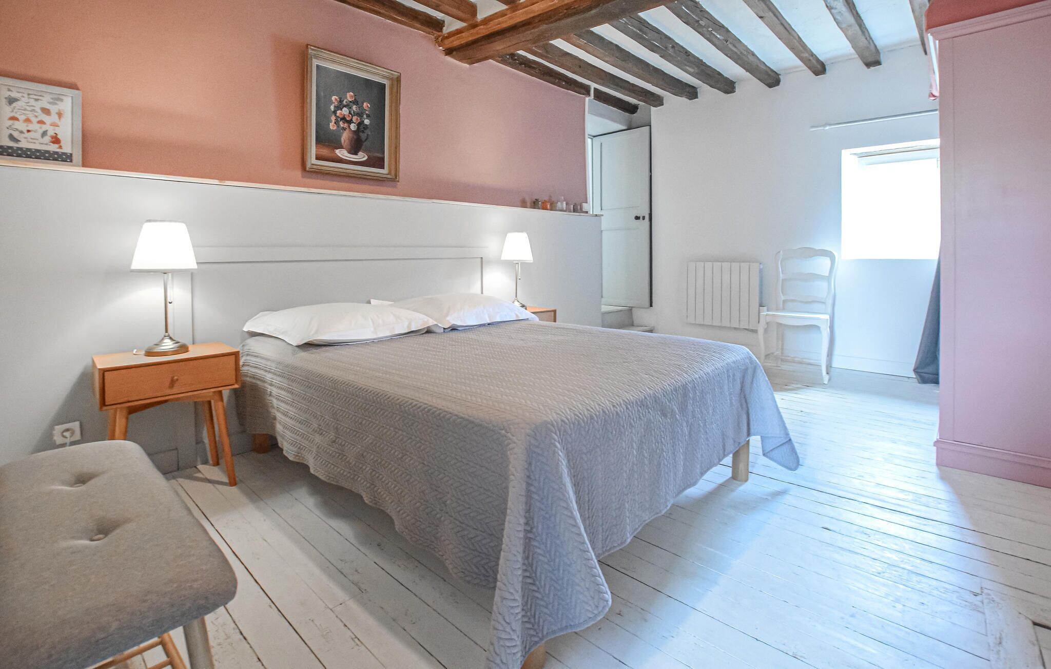 Une chambre à coucher comprenant un lit, des tables de chevet, une chaise, une commode, un miroir et une fenêtre.