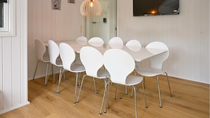 Ein Essbereich mit einem weißen Tisch und Stühlen, einer Pendelleuchte und Holzboden.