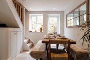 A dining area with a wooden table set for four, a bench, and a staircase. - Beautiful Townhouse in the Cotswolds (Chipping Norton)