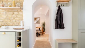 Eine Küche mit Backsteinwand, weißem Arbeitsplatz, Weinkühler und einer Garderobe.