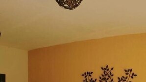 Una cama con ropa de cama blanca y varias almohadas, un adorno de árbol montado en la pared y una puerta visible a la izquierda.