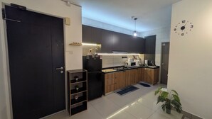 A modern kitchen with a black refrigerator, wooden cabinets, a microwave, and a sink.