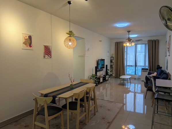 Un salon moderne comprenant un coin repas, un téléviseur et une grande fenêtre avec des rideaux.
