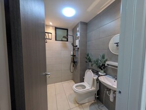 Une salle de bain moderne équipée de toilettes, d’un lavabo, d’une douche et d’un miroir.