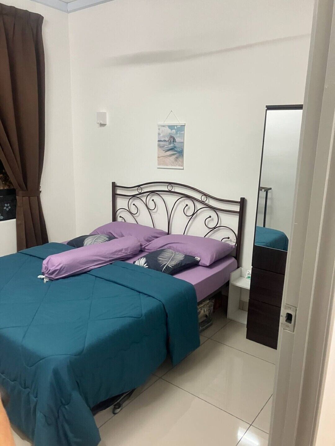 Une chambre à coucher avec un lit, une table de chevet, un miroir et un tableau accroché au mur.