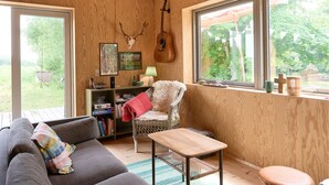 Ein gemütliches Zimmer mit Holzvertäfelung, einer Gitarre, einem gerahmten Bild und einem Korbstuhl.