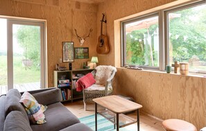 A cozy room with a wooden interior, a guitar, a framed picture, and a wicker chair. - 2 bedroom lovely home in Hasle (Hasle)
