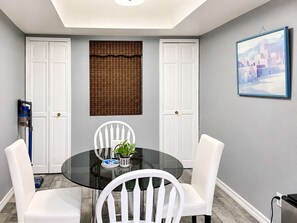 A dining area with a round glass table, white chairs, a decorative wall hanging, and a framed picture. - Pet-Friendly 2BR | Fenced Yard | 2 Community Pools (Scottsdale)