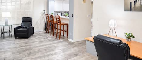 A modern interior with a dining area, a kitchen, and a desk with a chair.