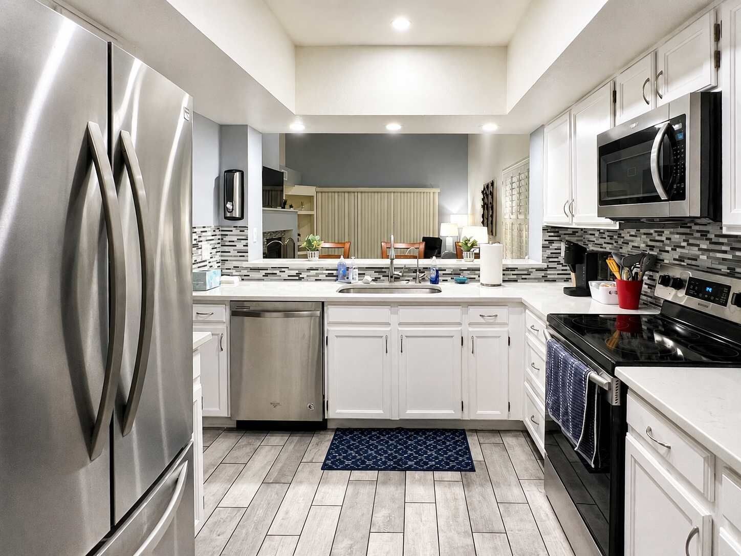 Een moderne keuken met roestvrijstalen apparatuur, witte keukenkastjes en een decoratieve achterwand.