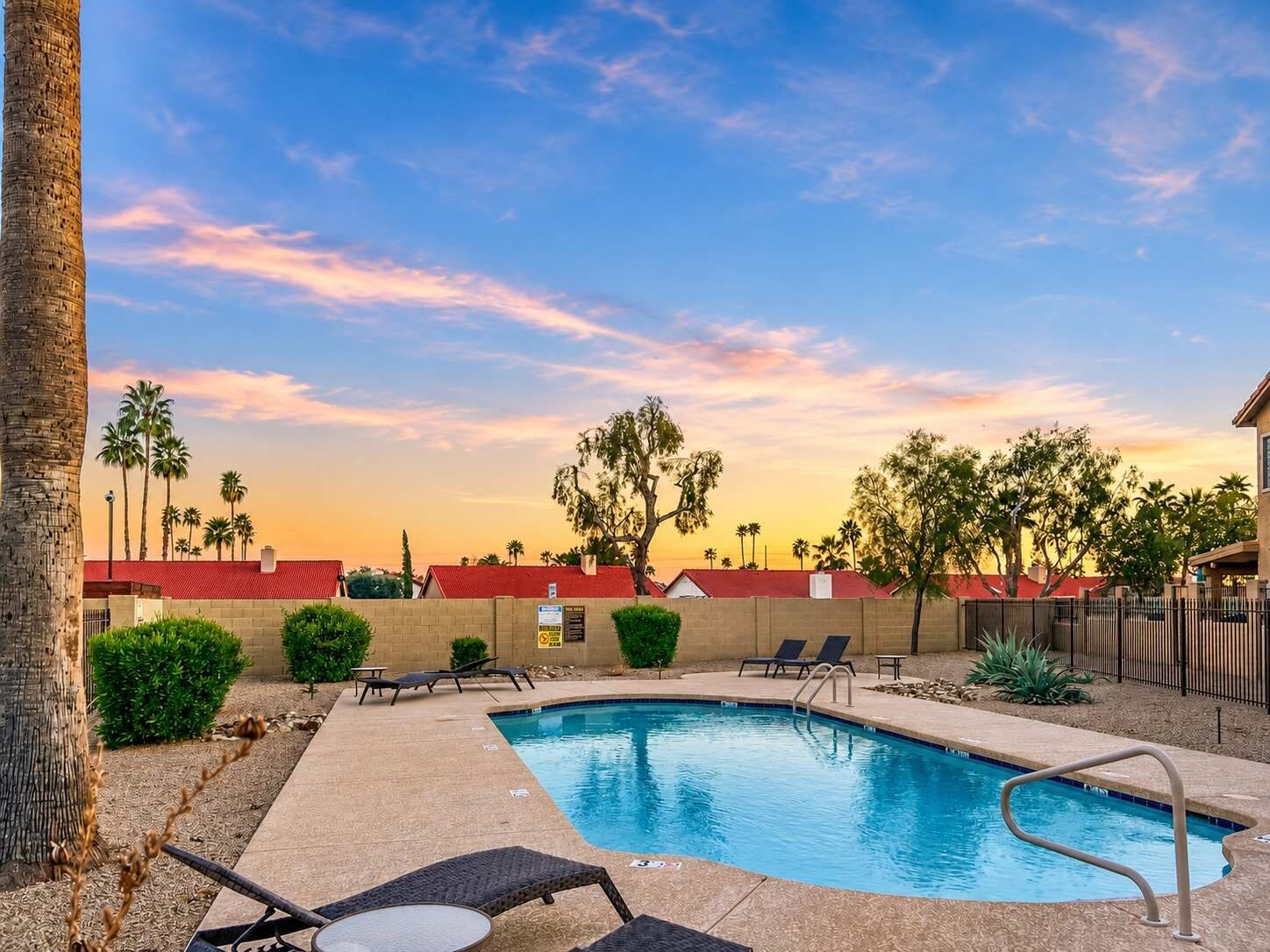 A swimming pool with lounge chairs and a clear sky.