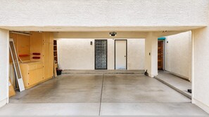 A covered parking area with a concrete floor, two doors, and a wooden structure with shelves. - Pet-Friendly 2BR | Fenced Yard | 2 Community Pools (Scottsdale)