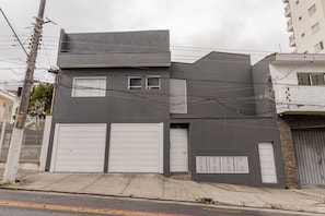 Un edifici modern de dues plantes amb garatge, una petita finestra i una unitat de ventilació.