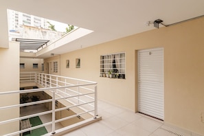 Um interior em vários níveis, com escadas, uma porta fechada e uma janela com persianas.