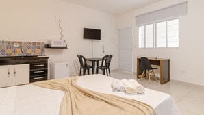 Een hotelkamer met een bed, een bureau, een televisie, een raam en een kitchenette.