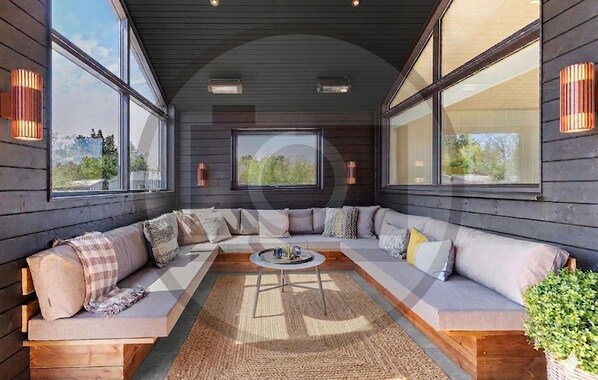 A modern interior with a large sectional sofa, a coffee table, and large windows offering views of the outdoors. - Gorgeous home in Rødby with sauna (Rødby)