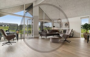 A spacious living area with a large sliding glass door leading to an outdoor patio, a comfortable sofa, and a dining table with chairs. - Gorgeous home in Rødby with sauna (Rødby)