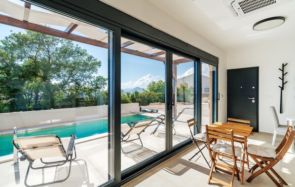 A modern interior with a pool, glass doors, and a dining area. - Amazing home in Budva (Budva)