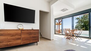 Un salon moderne doté d’un téléviseur à écran plat, d’un meuble en bois et d’un coin repas avec des sièges extérieurs.
