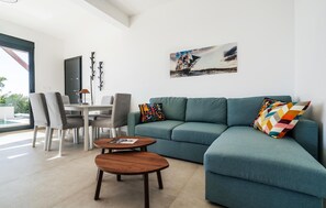 A modern living room with a teal sofa, two wooden coffee tables, and colorful throw pillows. - Amazing home in Budva (Budva)