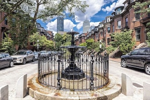 A fountain in a circular stone basin surrounded by a metal fence, with brick buildings and parked cars in the background. - Luxury 1 BR condo in South-End Boston, walk to Back Bay, Prudential, Copley (Boston)