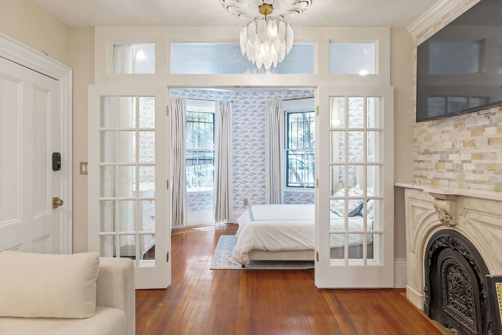 A room with a bed, a fireplace, and a chandelier.