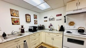 A kitchen with white cabinets, a granite countertop, a microwave, a kettle, and various wall decorations. - Welcome to the Tree House apartment- a family friendly retreat with arcade games (Lake Forest Park)