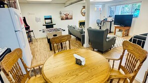 A round wooden table with chairs, a foosball table, a television, and a window with a view. - Welcome to the Tree House apartment- a family friendly retreat with arcade games (Lake Forest Park)