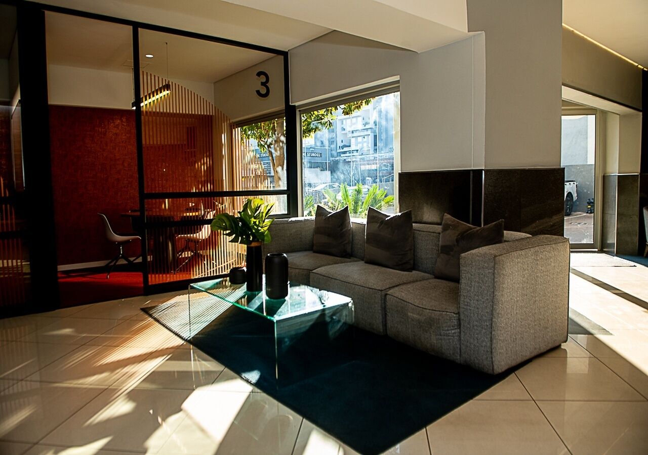 Una sala de estar moderna con un sofá modular, una mesa de centro de vidrio y vistas de la ciudad a través de amplios ventanales.