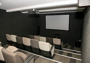 Ein Kino mit Sitzreihen, einer Leinwand und einem Projektor.