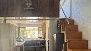 A compact kitchen with wooden flooring, a built-in stove, and a refrigerator.