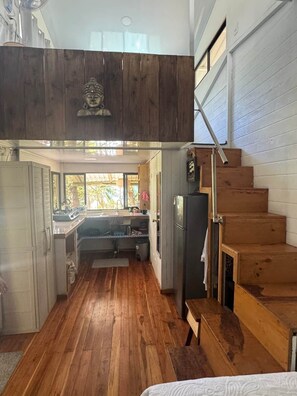 Eine kleine Küche mit Holzboden, einem Einbauherd und einem Kühlschrank.