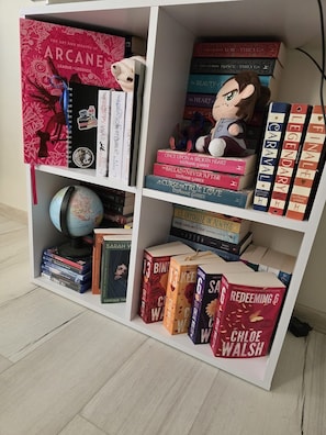 Ein Bücherregal mit verschiedenen Büchern, einem Globus und einem Stofftier.