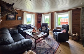 Ein gemütliches Blockhaus-Interieur mit Ledersofas, einem Couchtisch und einem aufgehängten Tierkopf.
