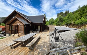 Eine Holzhütte mit einer Terrasse, Sitzgelegenheiten im Freien und einem Grillbereich.