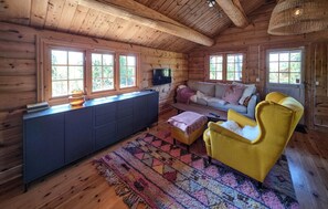 A log cabin interior with a sofa, yellow armchair, and a television on a wall. - Nice home in Tuddal with house a mountain view (Tuddal)