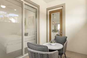 Ein Balkon mit einem Bett, einem Esstisch mit Stühlen und Blick ins Innere.
