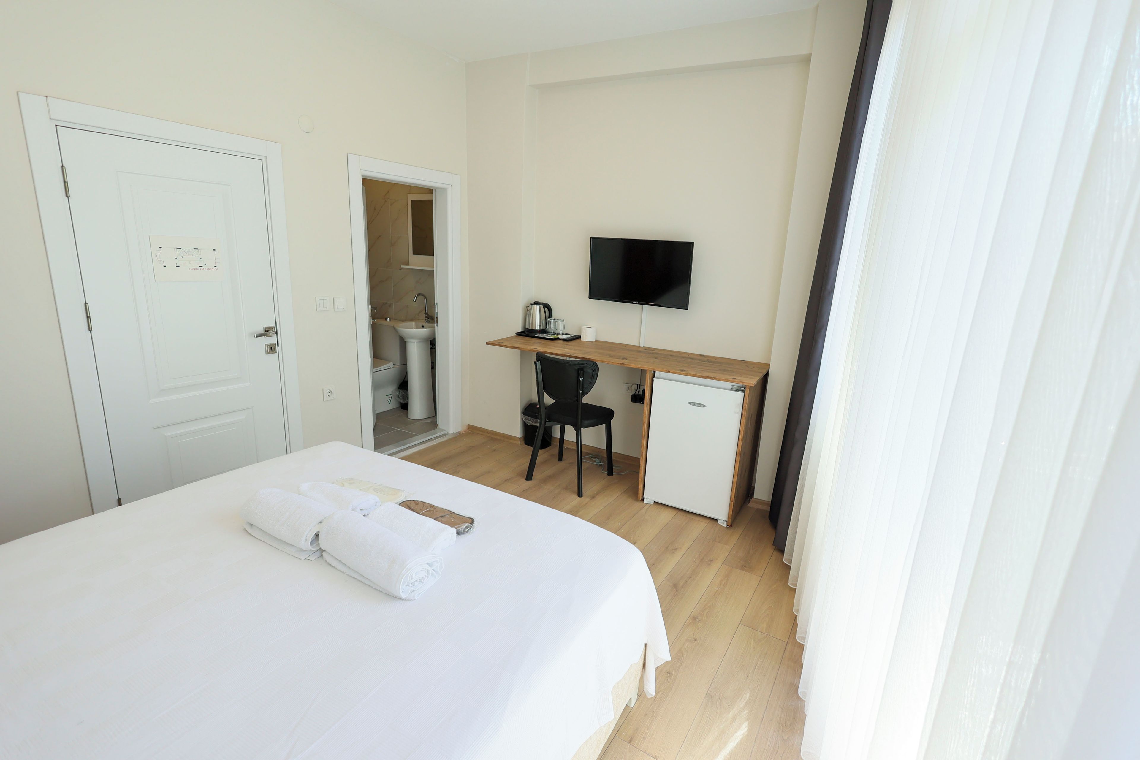 Una habitación de hotel con una cama, un escritorio con televisor y un refrigerador pequeño.