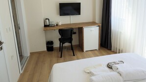 A hotel room with a bed, a desk with a computer, a chair, a small fridge, and a TV on the wall. - Taksim Heli Suites (Istanbul)