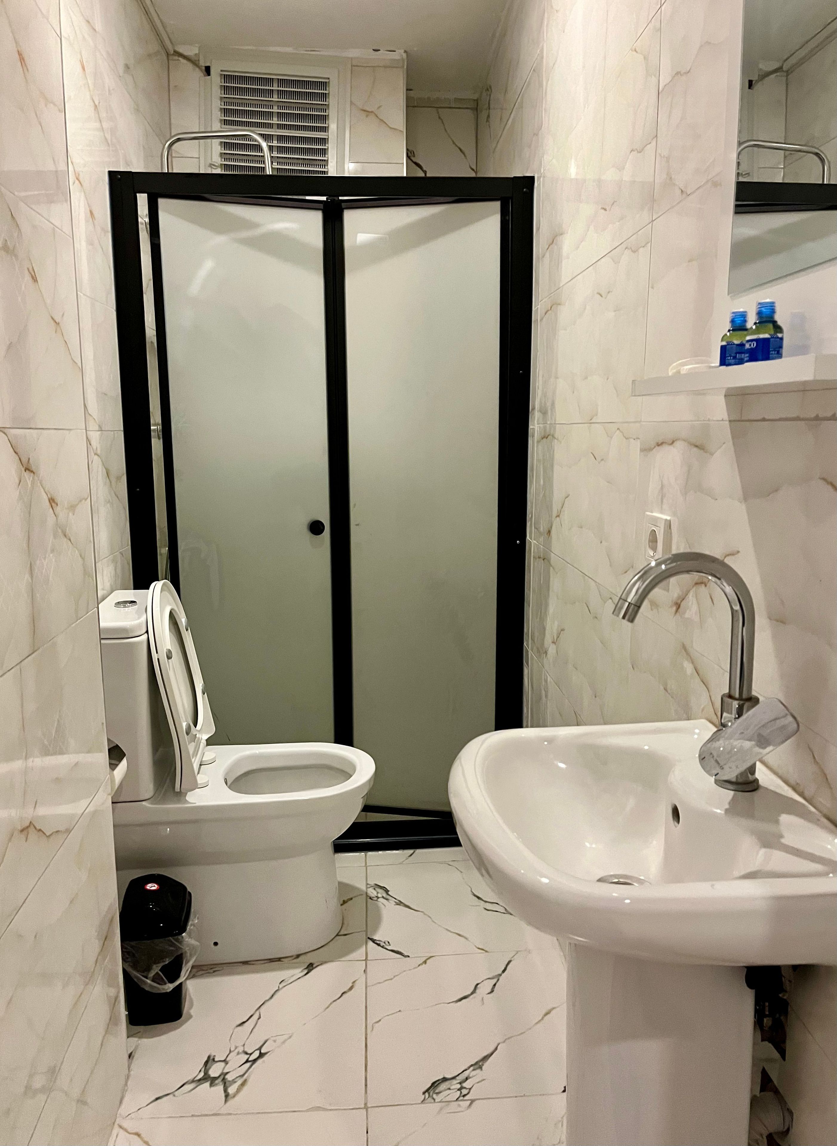 Un baño con inodoro, bidé, lavabo y cabina de ducha.