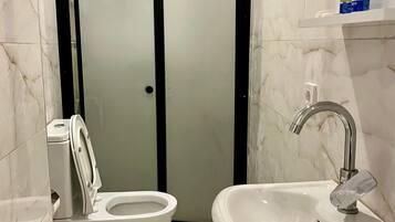 Un baño con inodoro, bidé, lavabo y cabina de ducha.