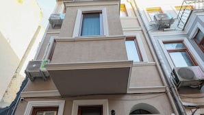 A multi-story building with a flat facade, multiple windows, and a central entrance with a black door. - Taksim Heli Suites (Istanbul)