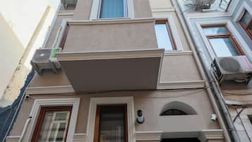 A multi-story building with a flat facade, multiple windows, and a central entrance with a black door.