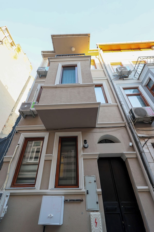 A multi-story building with a flat facade, multiple windows, and a central entrance with a black door. - Taksim Heli Suites (Istanbul)