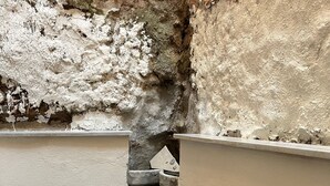 A patio area with a table and chairs, stone flooring, and a textured wall. - Taksim Heli Suites (Istanbul)