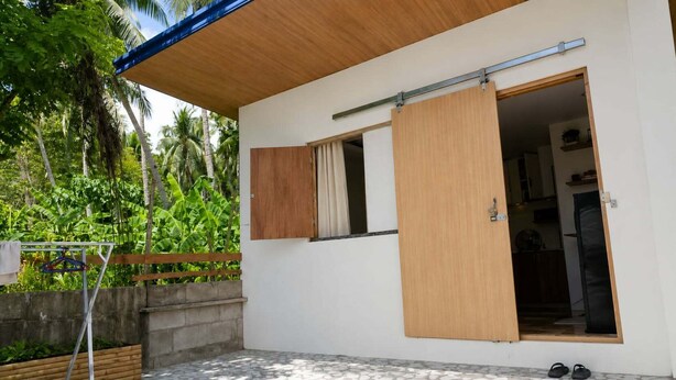 Une maison moderne dotée d’une porte coulissante, d’un plafond en bois et d’un plancher en béton.