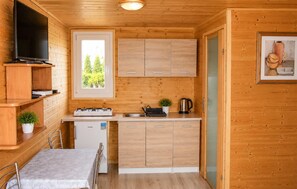 Una cocina compacta con armarios de madera, una estufa a gas, un lavamanos y un refrigerador pequeño.