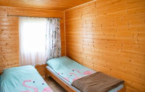 Ein Einzelbett aus Holz mit einem blumigen Vorhang und einer hellblauen Bettdecke.